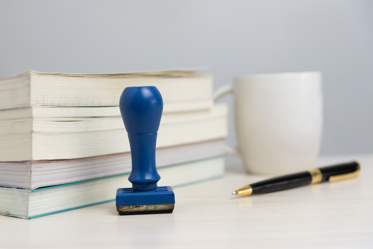 Book and rubber stamp and pen on desk at office Business concept.